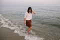 Happy carefree woman walking barefoot in cold sea waves on  sandy beach, enjoying tranquil evening Royalty Free Stock Photo