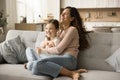 Happy carefree mom tickling cheerful daughter kid on sofa