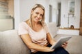 Happy, carefree and relaxed senior woman browsing on a tablet, enjoying her retirement and sitting on the sofa at home Royalty Free Stock Photo