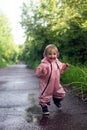 Happy carefree toddler girl running throuh the puddles after rain in summer day. Vertical fromat Royalty Free Stock Photo