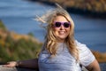 Happy carefree woman stands with blond hair blowing in wind at a scenic overlook in the Porcupine Mountains of Michigan