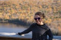 Happy carefree woman stands with brown hair blowing in wind at a scenic overlook in the Porcupine Mountains of Michigan