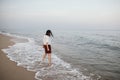 Happy carefree woman walking barefoot in cold sea waves on  sandy beach, enjoying tranquil evening Royalty Free Stock Photo