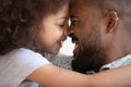 Happy caring african american man touching foreheads with smiling daughter. Royalty Free Stock Photo