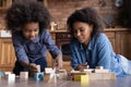 Happy caring African American mother with little daughter building tower