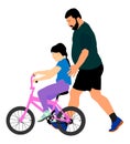 Happy caring father teaching his small young pretty daughter riding a bicycle .