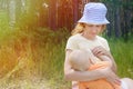 Caring mother breastfeeds her little son while sitting on the shore of a forest lake on a summer sunny day Royalty Free Stock Photo