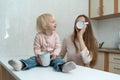 Happy caring mum and fair-haired girl drink milk at the kitchen