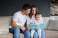 Happy caring parents reading a book to their child while sitting on the couch at home.Spending time together, learning. Royalty Free Stock Photo