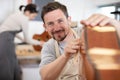 happy carpenter sanding guitar at workshop Royalty Free Stock Photo