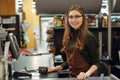 Happy cashier woman on workspace in supermarket shop. Royalty Free Stock Photo