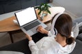 Happy casual beautiful Asian woman working on a laptop while sitting on sofa in living room at her home Royalty Free Stock Photo