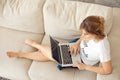 Happy casual beautiful woman working on a laptop sitting on the bed in the house. Royalty Free Stock Photo