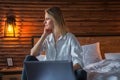 Happy casual beautiful woman working on a laptop sitting on the bed in the house Royalty Free Stock Photo