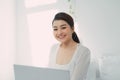 Happy casual beautiful woman working on a laptop sitting on the bed in the house Royalty Free Stock Photo