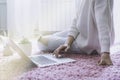 Happy casual beautiful woman working on a laptop sitting on the floor in the house. Royalty Free Stock Photo