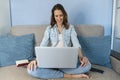 Happy casual beautiful woman working on a laptop sitting on the sofa in the house Royalty Free Stock Photo