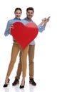 Happy casual couple holding big red heart is presenting something Royalty Free Stock Photo