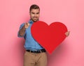 Happy casual guy in denim shirt holding big red heart and smiling Royalty Free Stock Photo