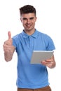 Happy casual man working on tablet makes ok sign