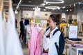 Happy casual woman shopaholic looking label price on pink dress at store boutique enjoying sale discount. Royalty Free Stock Photo