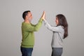 Happy caucasian aged husband and wife celebrating victory, give high five, isolated on gray background