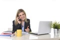 Happy Caucasian blond business woman working talking on mobile phone at office computer desk Royalty Free Stock Photo