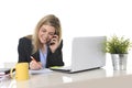 Happy Caucasian blond business woman working talking on mobile phone at office computer desk Royalty Free Stock Photo