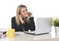 Happy Caucasian blond business woman working talking on mobile phone at office computer desk Royalty Free Stock Photo