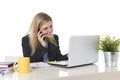 Happy Caucasian blond business woman working talking on mobile phone at office computer desk Royalty Free Stock Photo