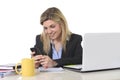 Happy Caucasian blond business woman working using mobile phone at office computer desk Royalty Free Stock Photo