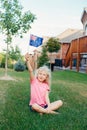 Happy Caucasian blonde girl holding Australian flag. Smiling child sitting on grass in park waving Australia flag. Kid citizen Royalty Free Stock Photo