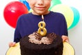 Happy caucasian boy celebrates birthday by holding a chocolate cake in his hands with candle and enjoying holiday Royalty Free Stock Photo