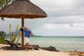 Happy caucasian boy plays on one of the best Mauritius beach on rainy cloudy day, catches ball to flying disk in a jump.