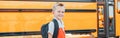 Happy Caucasian boy student with backpack near yellow bus on first September day. Education and back to school in autumn fall. Royalty Free Stock Photo