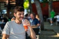 Happy caucasian brunette young man drinking a smoothie with a straw in a terrace Royalty Free Stock Photo