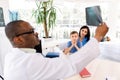 Happy Caucasian child boy with mom at consultation in modern clinic, sitting at the table, while african man Royalty Free Stock Photo