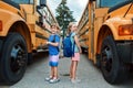 Happy Caucasian children boy and girl kids students standing by yellow school bus. Education and back to school in September. Royalty Free Stock Photo