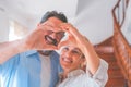 Happy caucasian couple embracing each other in the living room and making heart shape symbol with hands. Loving husband and wife Royalty Free Stock Photo