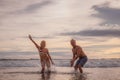 Happy Caucasian couple playing with water on the beach. Smiling and laughing young man and woman enjoying life. Sunset time. Royalty Free Stock Photo