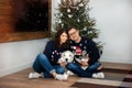 Happy caucasian couple sitting near christmas tree with big white dog. Couple or marriage in his new home. Love, trust, Royalty Free Stock Photo