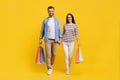 Happy Caucasian Couple Walking With Bright Shopping Bags On Yellow Studio Background Royalty Free Stock Photo