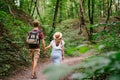 Happy caucasian couple are walking in a dense forest along the path holding hands, rear view. Hikers with backpack looking for Royalty Free Stock Photo