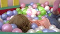 Happy caucasian cute blonde child having fun and playing in multi coloured ball pool at indoor playground. Preschool