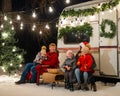 Happy Caucasian family celebrating Christmas outdoors. Parents and three sons travel in a camper. Royalty Free Stock Photo