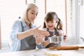 Happy Caucasian family enjoying spend time together in the kitchen. Beautiful mom is caring and teaching adorable daughter helping Royalty Free Stock Photo