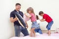 Happy Caucasian Family of Four Having a Playful Funny Pillow Fight on Bed Indoors with Positive Emotions Royalty Free Stock Photo