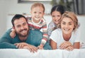 Happy caucasian family of four in pyjamas cosy together in bed at home. Two little kids lying on top of their loving Royalty Free Stock Photo