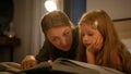 Happy Caucasian family loving caring mother reading book to little kid daughter using flashlight in bedroom lying on bed Royalty Free Stock Photo