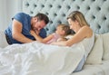 Happy caucasian family lying in bed with two daughters. Two little girls looking happy while being playful and Royalty Free Stock Photo